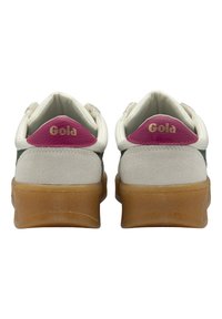 Zapatillas blancas y grises con una suela de goma, que presentan detalles en rosa en la parte posterior, una textura de gamuza y un logo "Gola" en color dorado.