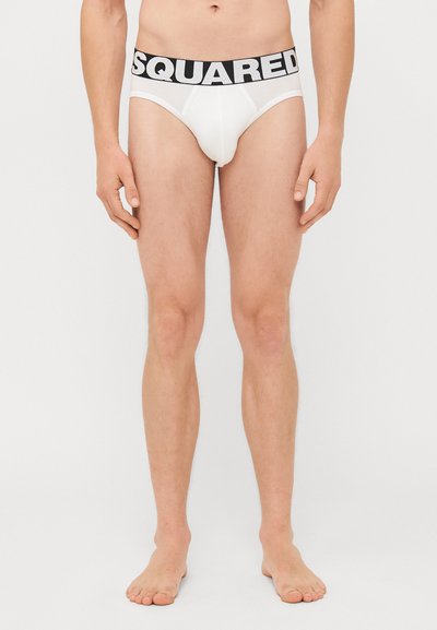 Caleçons blancs pour hommes avec une ceinture logo "SQUARED" noire ; tissu lisse, coupe ajustée, détails de couture à l'avant, et sans motifs visibles.
