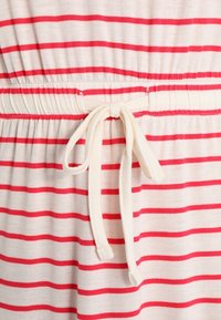 Raidoitettu mekko vaaleassa sävyssä, jossa on punaisia vaaleita vaakaraitoja. Mekon vyötärö on joustava ja siinä on keskellä saman materiaalin valmistama nauha.