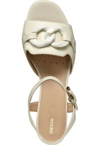 Sandalo platform beige con una ampia fascia, caratterizzato da un dettaglio a catena bianca lucida. Include un cinturino alla caviglia con una fibbia in tono oro.