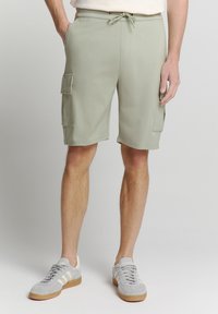 Lichtgroene cargoshorts met een elastische tailleband en koord. Voorzien van twee zijzakken en twee cargozakken op de dijen.