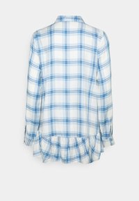 Blouse blanche à manches longues avec motif à carreaux bleu, avec un col et un détail volanté à l’ourlet vue de dos.