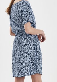 Modré květinové šaty s krátkými rukávy, s vypasovaným pasem a volným střihem. Vyrobené z lehké tkaniny s jemnou texturou.