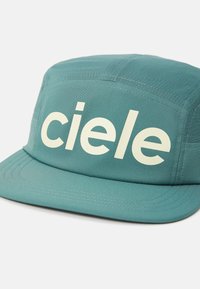Teal cap with a flat brim, featuring the word "ciele" in large cream letters on the front. Made of lightweight fabric with textured surface.