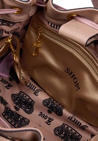 Helles rosa Lederhandtascheninnere mit goldenen Beschlägen. Verfügt über eine Reißverschlusstasche, ein gedrucktes Kronenmuster und den Text "SHOP!" auf glattem Stoff.
