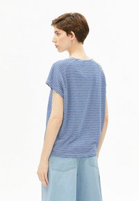 Blauw-wit gestreept T-shirt met korte mouwen, ronde hals en losse pasvorm; gedragen met lichtblauwe wijde denim broek.