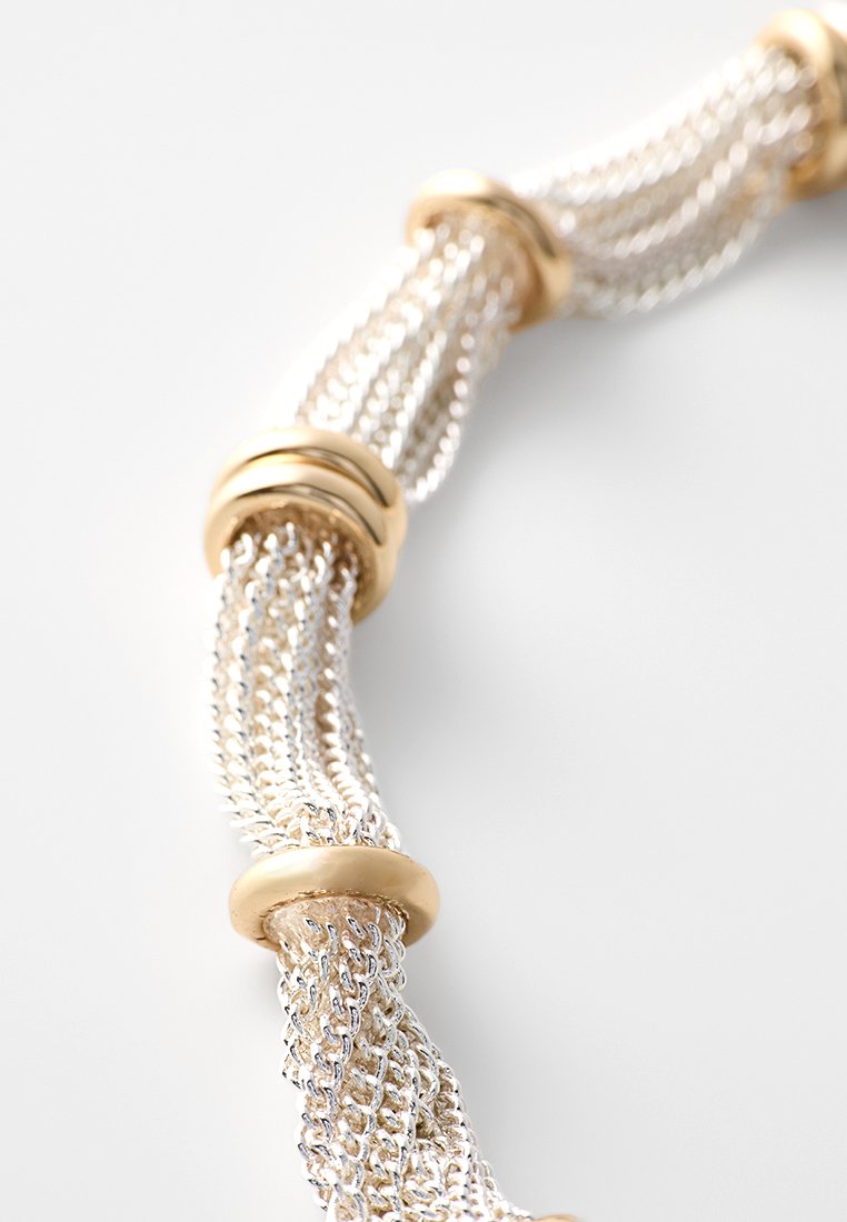 Collana in argento con maglie intrecciate, intervallate da accenti circolari in oro, caratterizzata da una texture liscia e un design fluido.