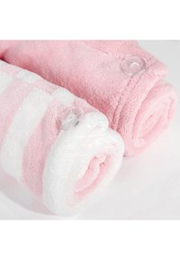 To håndklær rullet, ett ensfarget rosa og ett hvitt med rosa striper, laget av mykt, fluffy materiale. Klare knapper i endene.