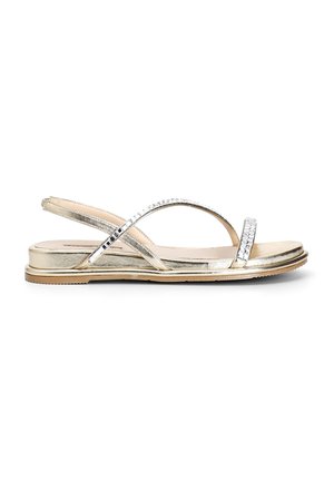 Sandali metallici dorati con suola piatta, cinturini incrociati e strass decorativi lungo il cinturino superiore per un tocco in più.