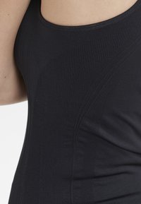 Svart linne i stretchigt material med ribbad textur och böljande designlinjer på sidorna för en figurnära look.