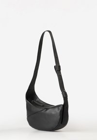 Borsa a spalla in pelle nera con design curvo e asimmetrico. Presenta una lunga tracolla regolabile e un compartimento con zip. Texture liscia.