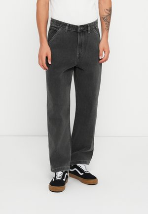 Gray denim jeans with a straight-leg cut, featuring visible stitching, and a button closure at the waistband. Worn with black sneakers.