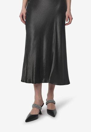 Black satin midi skirt with a soft sheen, paired with black pointed-toe heels featuring decorative rhinestone-embellished ankle straps.