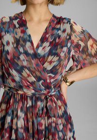 Robe portefeuille multicolore en tissu léger, avec un décolleté en V, des manches évasées et une ceinture à nouer à la taille, ornée d'un motif abstrait.