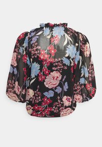 Blusa preta transparente com estampa floral em vermelho, rosa e azul. O decote franzido e as mangas bufantes criam uma forma volumosa com detalhes florais.