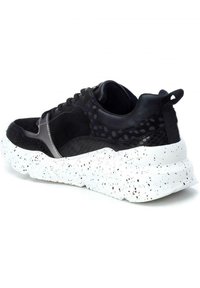 Sneaker nera con tomaia texturizzata in mesh e suede, suola spessa bianca con macchie, e un inserto per il tallone.
