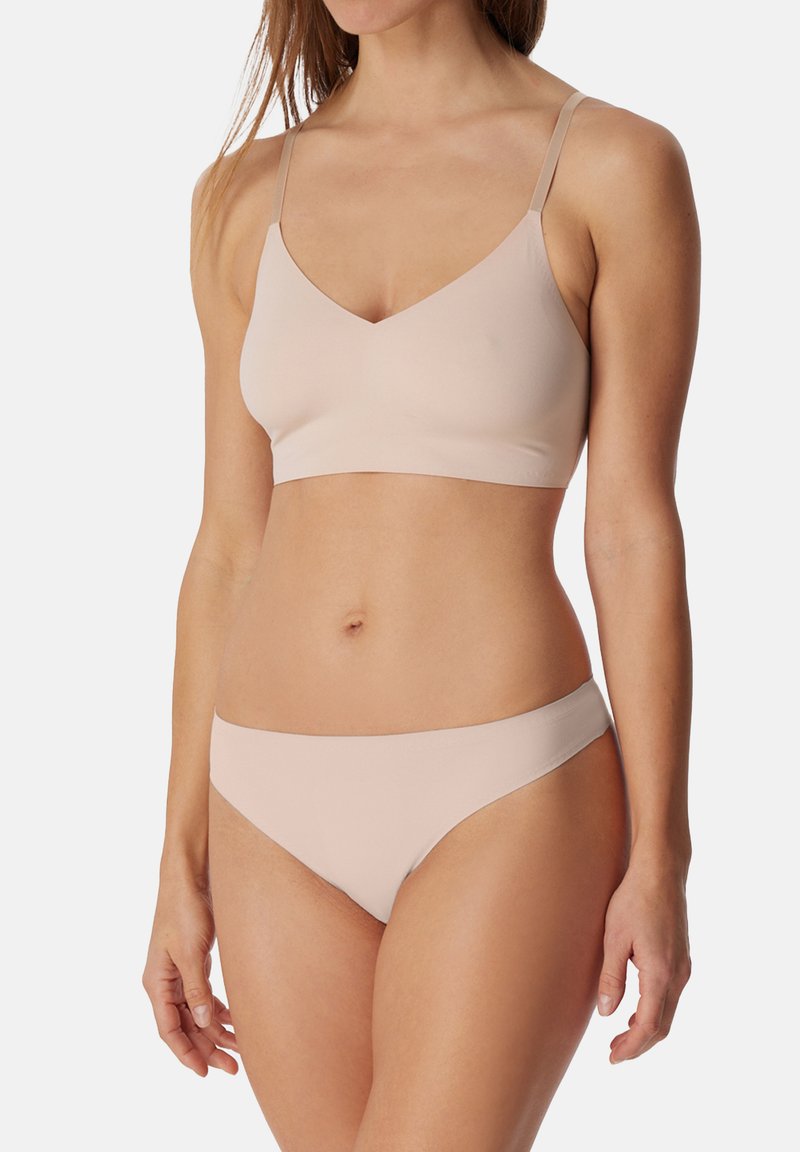 Reggiseno beige chiaro e mutandine bikini abbinate, realizzati in un morbido e liscio tessuto. Il reggiseno ha un design a scollo a V e spalline sottili.