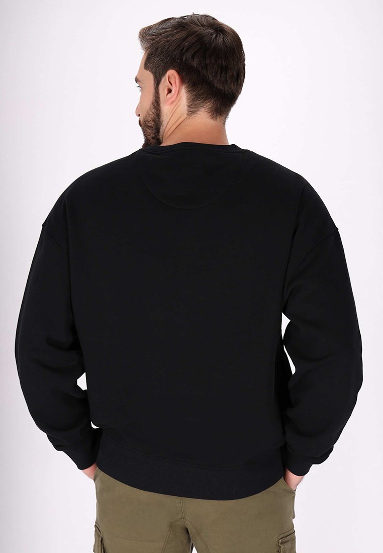 Schwarzer Hoodie aus weichem Stoff. Mit überschnittenen Schultern und gerippten Bündchen. Minimalistisches Design, glatte Textur.