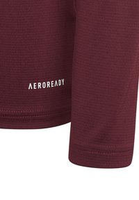 Bordeauxfarbenes Langarmshirt mit strukturierten Oberflächen. Verfügt über das weiße "AEROREADY"-Logo. Einfache Steppnähte entlang der Nähte.