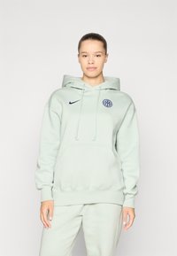 Lys grønn hettegenser med kengurulomme, snøring på hetten, ribbede mansjetter og brodert marineblå logo på brystet. Myk stofftekstur.