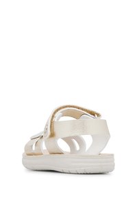 Sandalová obuv na páskách s kovově zlatým a bílým povrchem, vybavená nastavitelnou sponou, polstrovanou podrážkou a otevřeným designem pro podporu prodyšnosti.