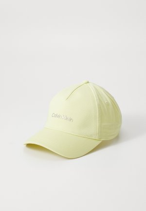 Căciulă galbenă dintr-un material neted, având o vizieră curbată și logo-ul brodat "Calvin Klein" pe față. Ușor texturată.