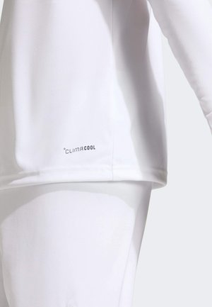 Close-up of a person wearing white clothing with "ClimaCool" logo on the lower side of the top, highlighting breathable fabric detail.