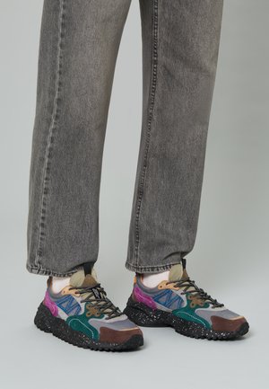 Sneaker multicolori caratterizzati da una combinazione di materiali grigi, verdi, viola e marroni, con una suola nera texturizzata e lacci a contrasto.
