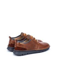 Zapatos de cuero marrón con un acento de tacón de ante, suela gris, cordones redondos y detalles de costura, con un diseño casual y perfil bajo.