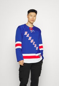 Tricou de hochei de culoare albastru royal, cu dungi roșii și albe, care prezintă inscripția "RANGERS" în litere albe. Mâneci scurte, guler cu șnur, logo-ul NHL pe guler.