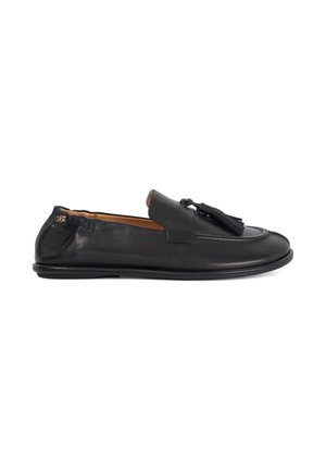 Mocassin à enfiler en cuir noir avec des pompons sur le dessus, bout arrondi, petit talon et doublure intérieure beige, présenté de profil sur un fond blanc.