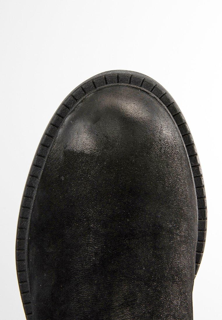 Botín de ante negro hasta el tobillo con puntera redondeada, parte superior texturizada y suela de goma con borde estriado para un mejor agarre.