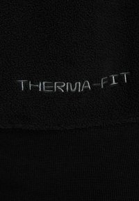 Schwarzer Therma-Fit-Stoff mit weicher Textur. Verfügt über das gestickte "THERMA-FIT"-Logo in Silber. Das Design kombiniert eine Fleece-Oberfläche mit gerippten Akzenten.