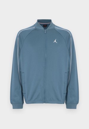 Giacca blu con zip e collo alto, strisce bianche di accento e piccolo logo sul petto sinistro. Realizzata in tessuto liscio e leggero.