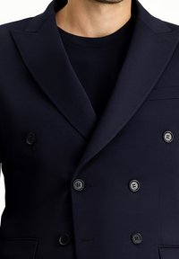 Granatowy, dwurzędowy blezer z klapami z wycięciami, sześć czarnych guzików i detal kieszeni. Gładka, teksturowana tkanina, dopasowany krój.