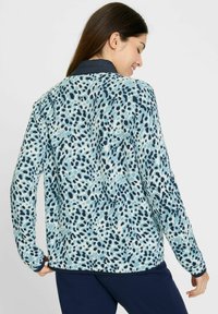 Leopardenmuster-Jacke in Hellblau und Marineblau, mit langen Ärmeln, einem Kragen und einem strukturierten Stoff, von hinten gezeigt.