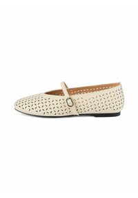 Zapato plano color crema con patrones calados, puntera redonda y una correa delgada con hebilla. Presenta una suela negra plana y un interior texturizado.