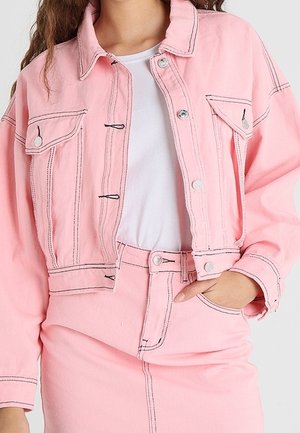 Rosa, taillierte Jeansjacke mit zwei Brusttaschen, silbernen Beschlägen und kontrastierendem Nähen. Kombiniert mit einem passenden rosa Jeansrock.