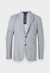 Heleda hallikas bleiser struktuurse kangaga, sakiliste lipsudega, kahe esipocketiga ja kahe musta nööbiga. Silt ütleb "JOOP! JEANS."