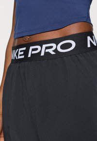 Nike Pro σορτς σε μαύρο χρώμα με φαρδύ ελαστικό ζωνάκι που φέρει λευκή σήμανση "NIKE PRO". Το ύφασμα φαίνεται ελαφρύ και απαλό.