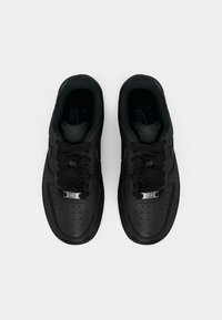 Um par de sapatilhas Nike Air Force 1 pretas com atacadores e biqueira perfurada, vistas de cima sobre um fundo branco.