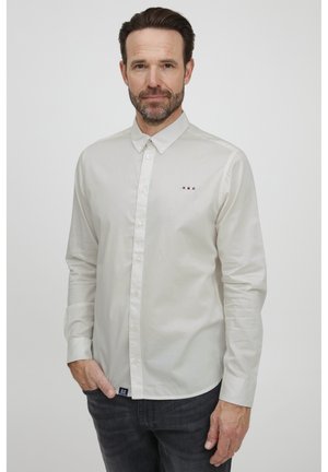 Lys farget knappopp skjorte laget av jevnt stoff. Har en liten logo med røde, hvite og blå striper nær brystet. Slim fit design.