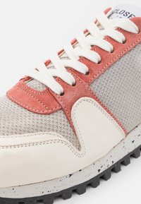 Baskets avec une tige en tissu gris clair, des accents en daim corail, des lacets blancs et une semelle extérieure en caoutchouc tachetée robuste avec une bonne adhérence.