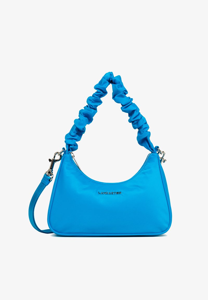 Sac à main en nylon bleu avec une bandoulière souple et froncée. Dispose d'un logo argenté et d'une fermeture éclair, accentué par un design épuré.