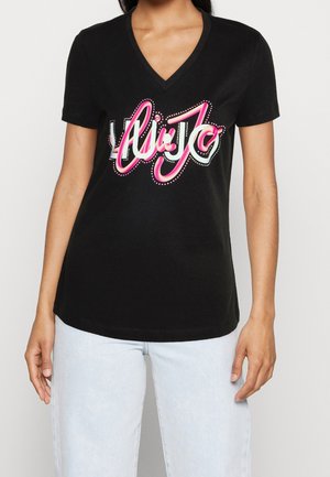 Schwarzes Baumwoll-T-Shirt mit V-Ausschnitt und kurzen Ärmeln, versehen mit auffälligem pinkfarbenem Schriftzug "Li Jo" und weißen Polka-Dot-Akzenten.