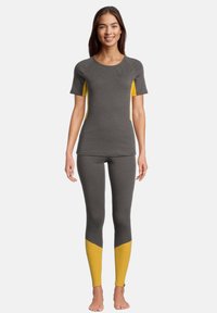 Top corto grigio a maniche corte con dettagli gialli e leggings grigi con dettagli gialli alle caviglie, realizzati in un materiale morbido e elasticizzato.