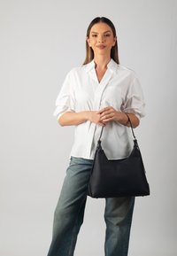 Black leather shoulder bag with a soft, textured surface and gold-tone hardware. Curved shape with a single adjustable strap.
