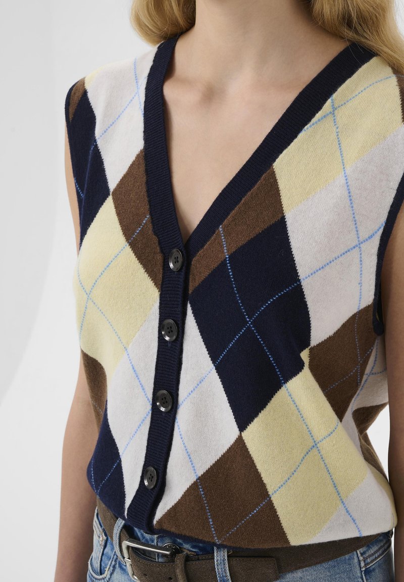 Vestă tricotată fără mâneci, cu decolteu în V, nasturi și un model argyle multicolor în nuanțe de bleumarin, maro, crem și galben, cu accente albastre.