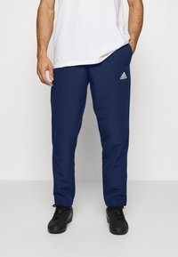 Marine treningsbukser laget av lett materiale, med rett snitt, elastisk midje og et lite hvitt Adidas-logo på venstre lår.