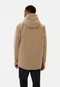 Beige waterdichte jas met een capuchon, elastische manchetten en een relaxte pasvorm. Gladde textuur, minimalistisch design, geschikt voor casual wear.
